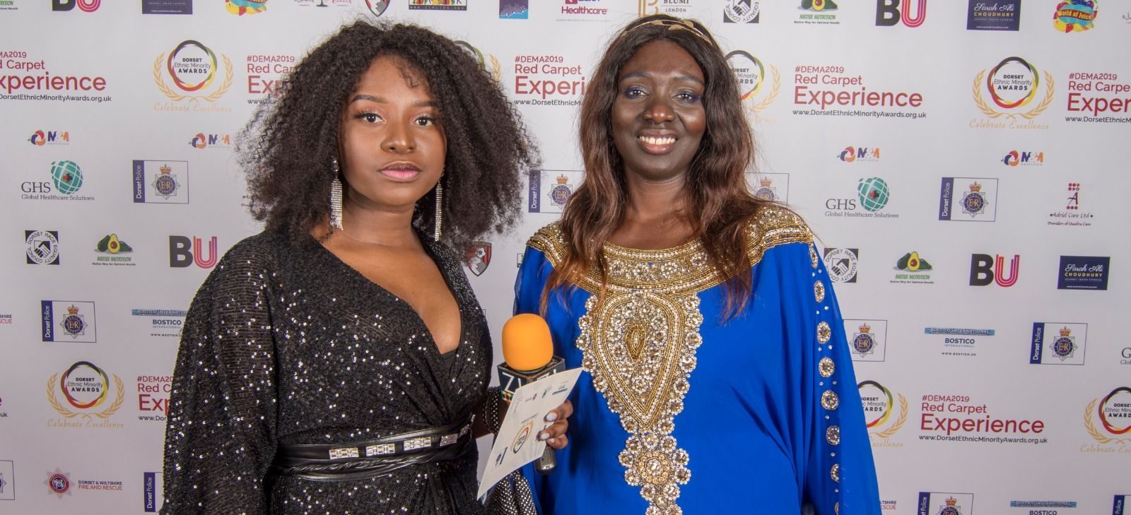 Two guests in gold and blue outfits on the red carpet