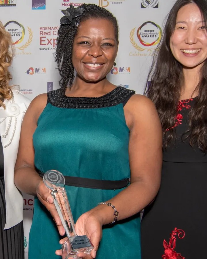 A winner holding a crystal trophy, flanked by two guests