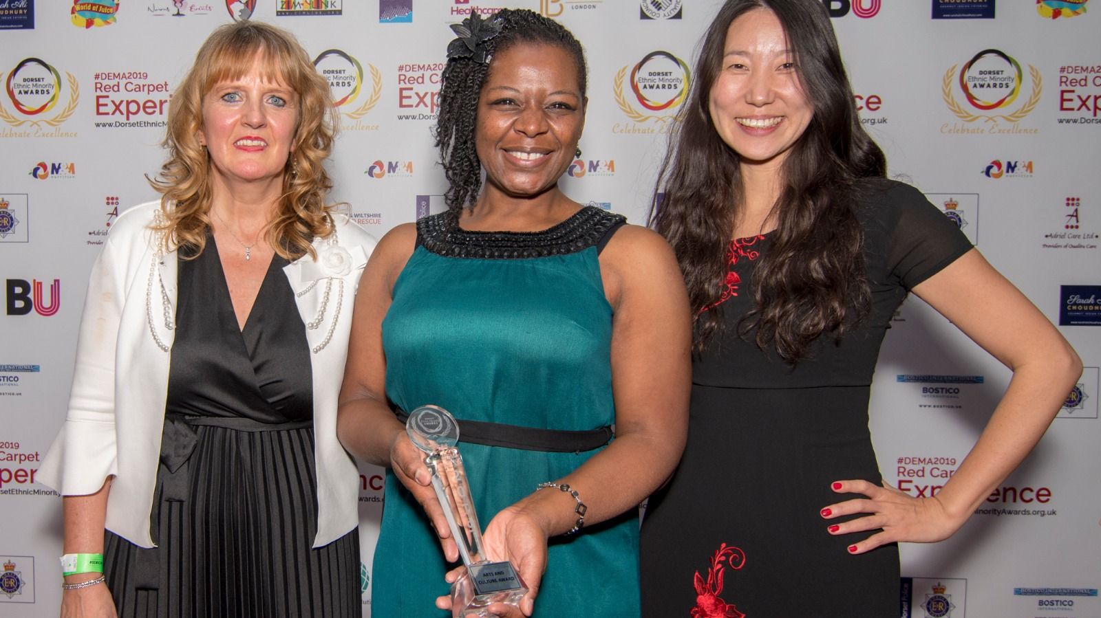 A winner holding a crystal trophy, flanked by two guests