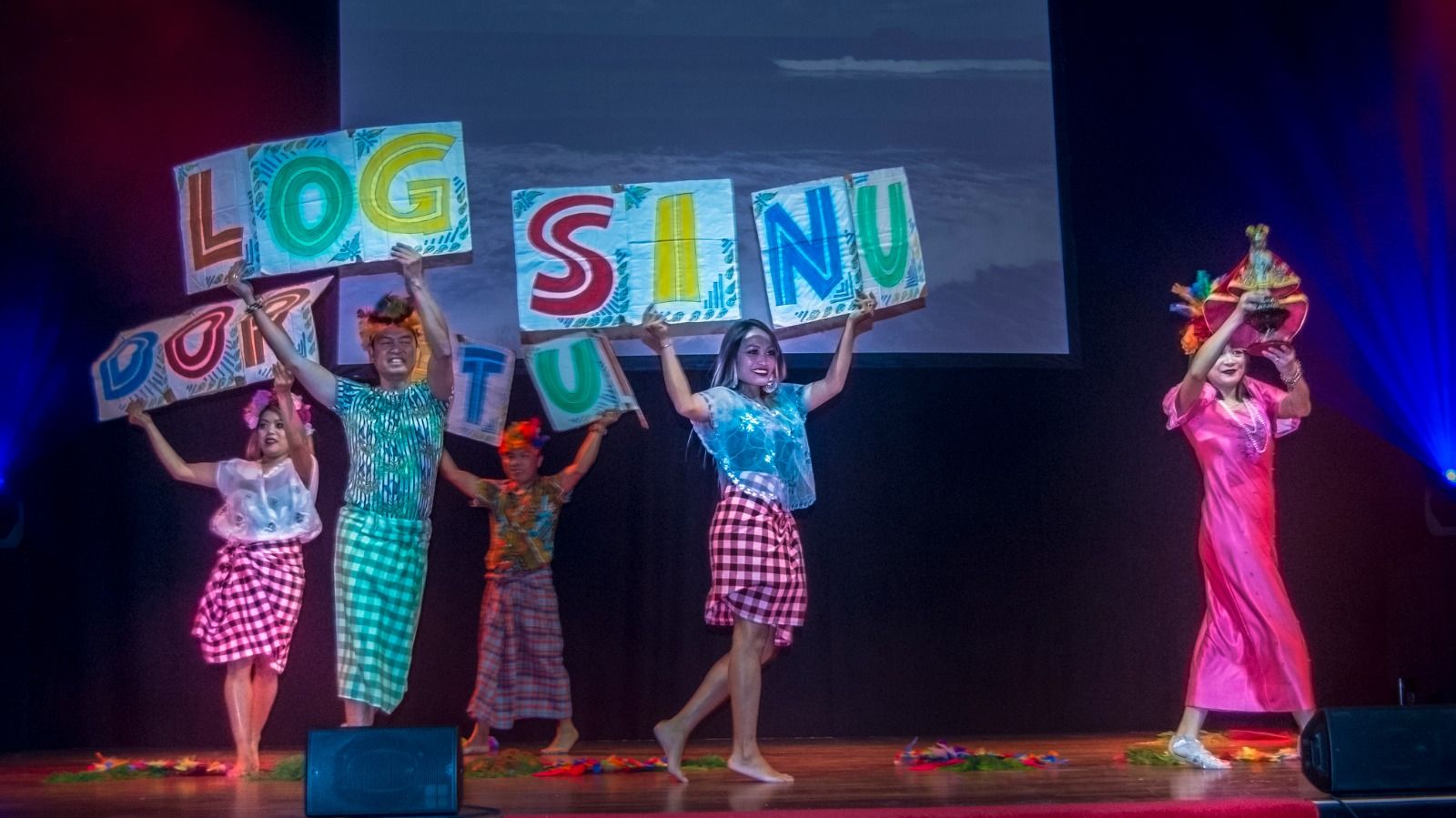 Performers on stage holding up colourful signs