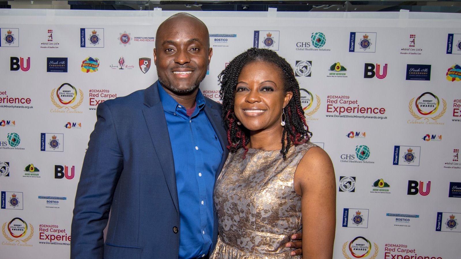 A couple in a blue suit and gold dress on the red carpet