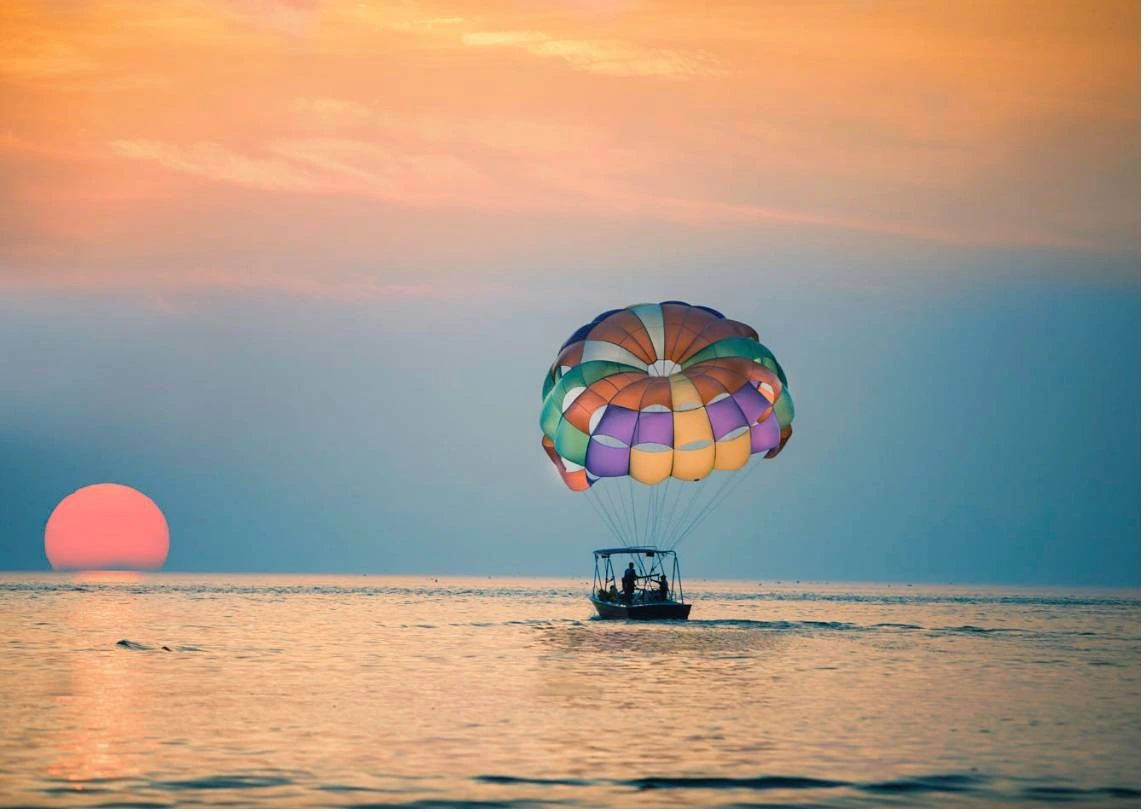 Parasailing nad Morzem Czerwonym w Sharm el Sheikh - kolorowy spadochron holowany przez motorówkę o zachodzie słońca