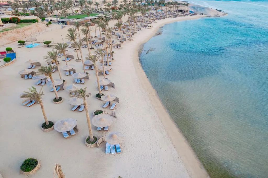 Szeroka piaszczysta plaża i turkusowa woda zatoki nad Morzem Czerwonym w rejonie Marsa Alam