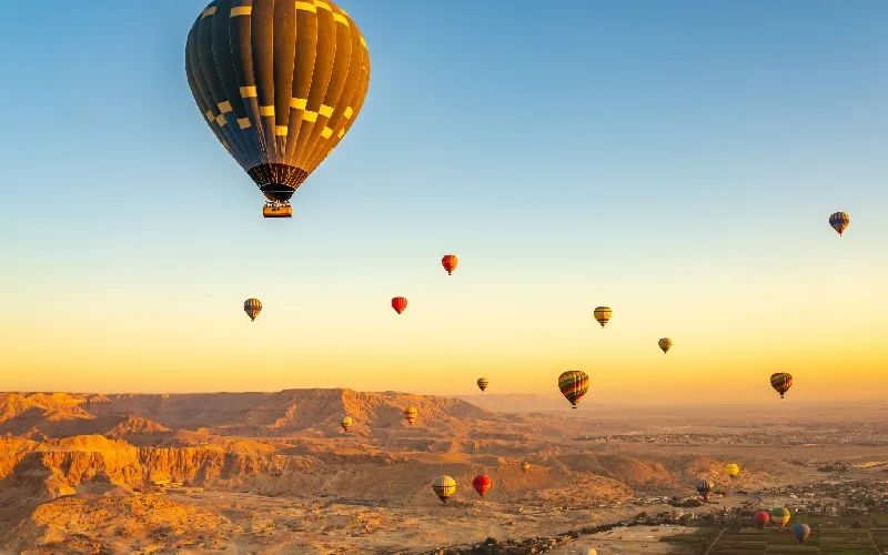 Balony na ogrzane powietrze nad doliną i pustynią w okolicy Luksoru o świcie