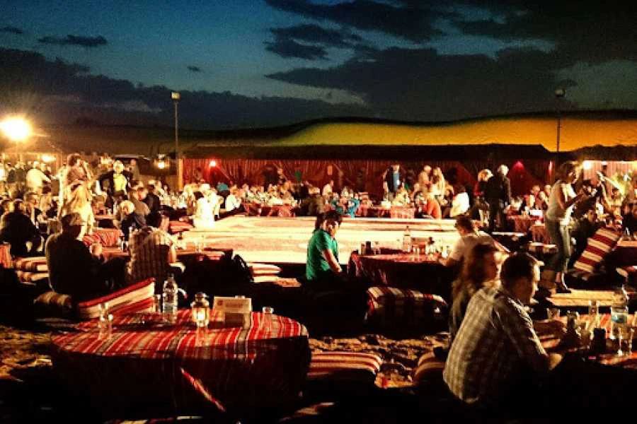 Rozświetlony wieczorem beduiński obóz z gośćmi przy kolacji podczas Jeep Safari z Marsa Alam
