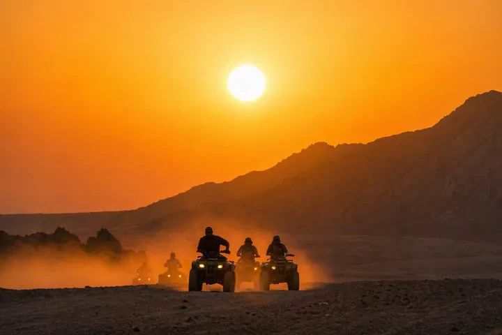 Konwój quadów jadący w stronę zachodzącego słońca na pustyni Synaj podczas safari z Sharm el Sheikh