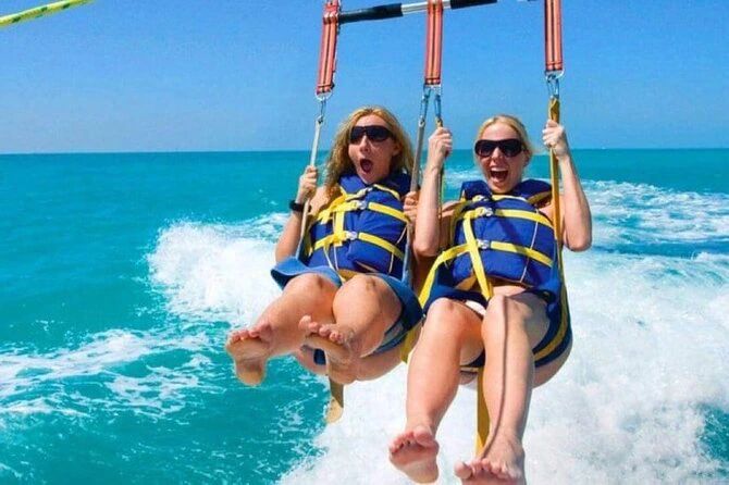 Dwie uczestniczki parasailingu w kamizelkach asekuracyjnych tuż nad taflą wody podczas lotu