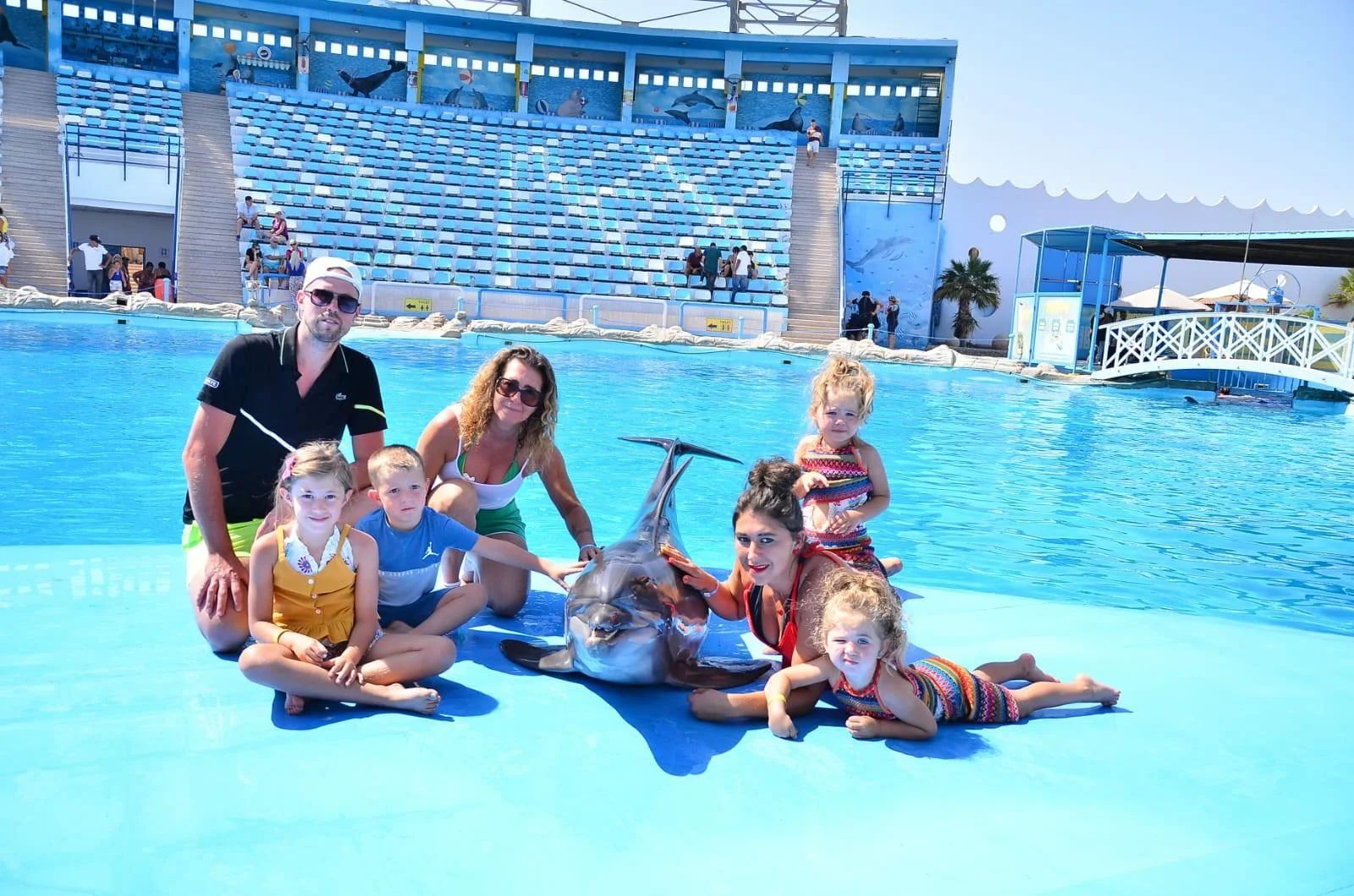 Rodzina pozująca z delfinem na tle areny delfinarium w Sharm el Sheikh