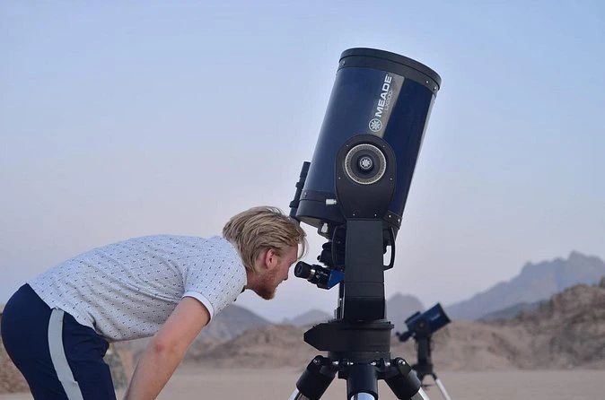 Uczestnik obserwujący nocne niebo przez teleskop na pustyni podczas Sunset Safari z Sharm el Sheikh