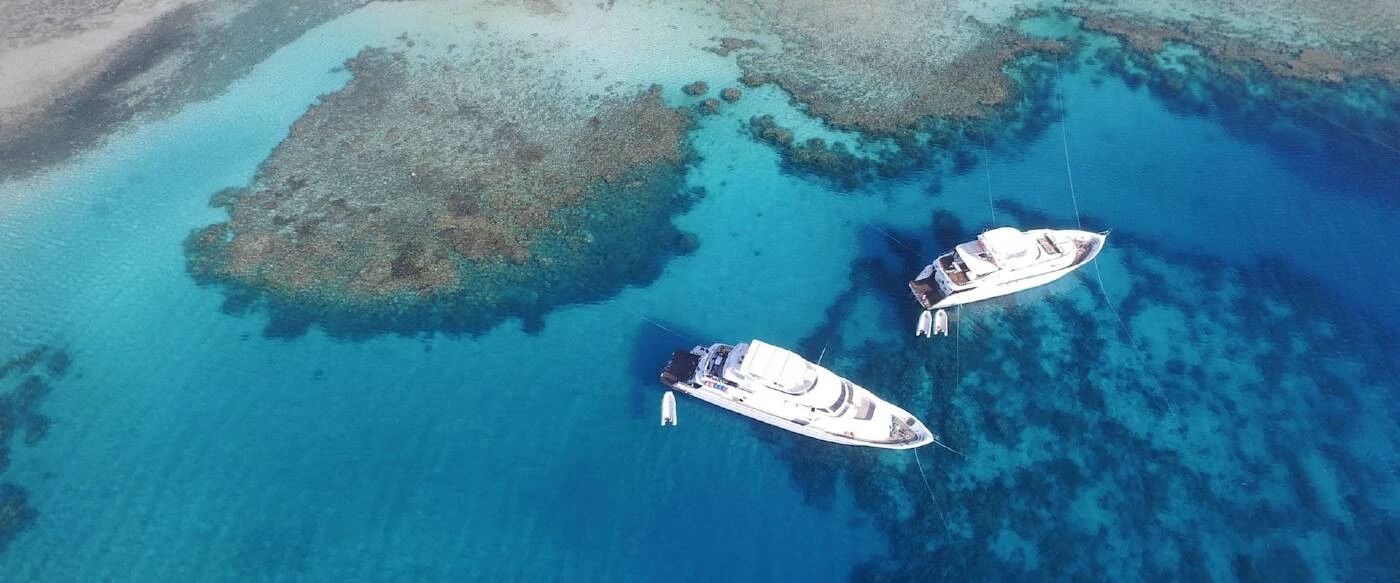Widok z lotu ptaka na rafy koralowe wokół Wyspy Tiran z zacumowanymi łodziami w turkusowej wodzie - rejs z Sharm el Sheikh