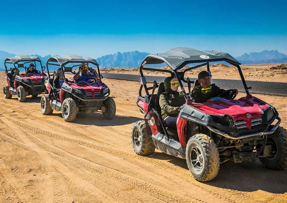 Kolumna czerwonych buggy jadących przez pustynię na tle gór Synaju podczas Buggy Safari z Sharm el Sheikh
