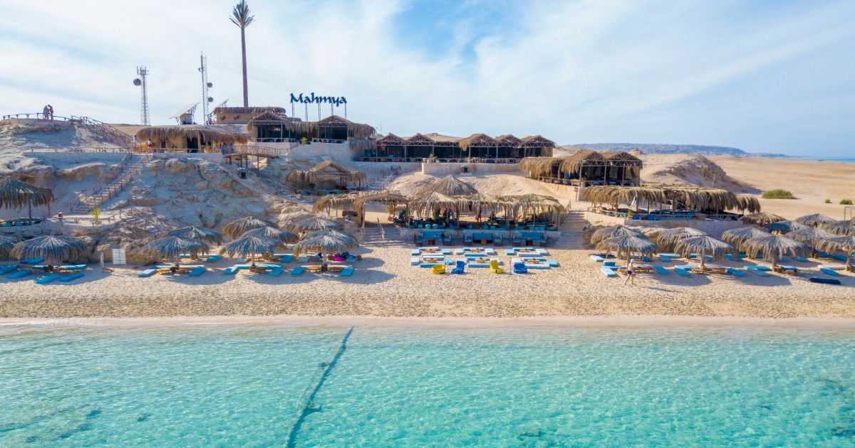 Wyspa Mahmya koło Hurghady z napisem Mahmya na wzgórzu, słomianymi parasolami i restauracją na plaży nad turkusową, płytką wodą Morza Czerwonego