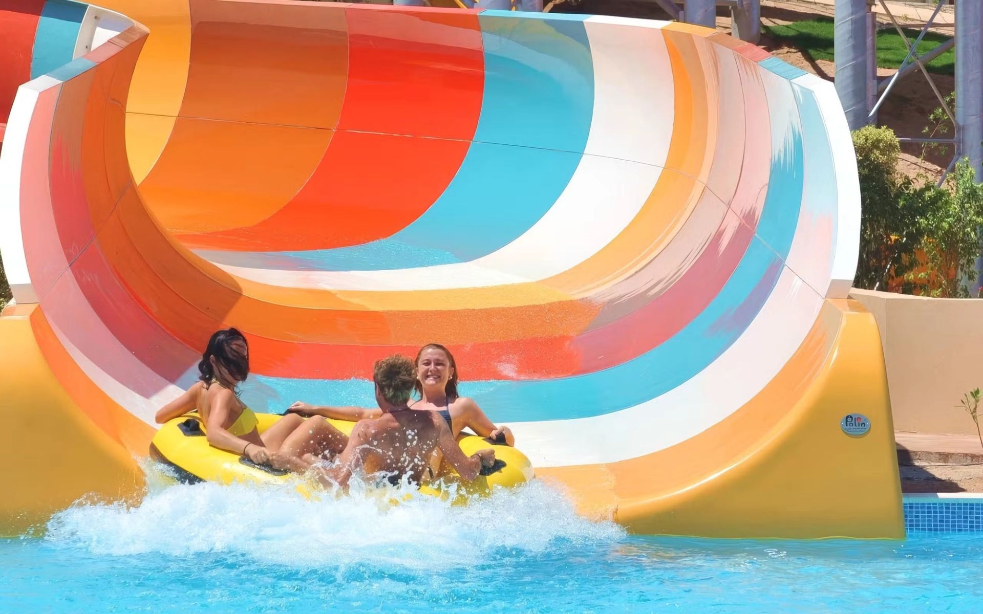 Trzy osoby zjeżdżające na pontonie kolorową zjeżdżalnią w aquaparku Makadi Water World