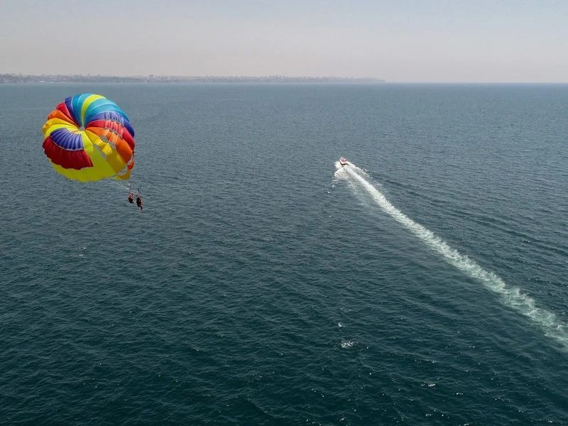 Spadochron parasailingowy i motorówka widziane z góry nad Morzem Czerwonym u wybrzeża