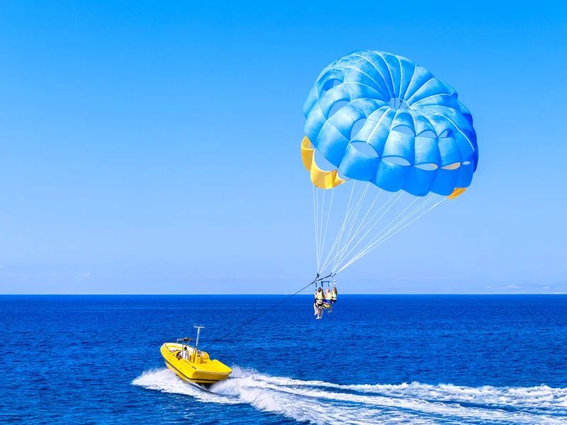 Spadochron parasailingowy holowany przez żółtą motorówkę nad błękitnym Morzem Czerwonym