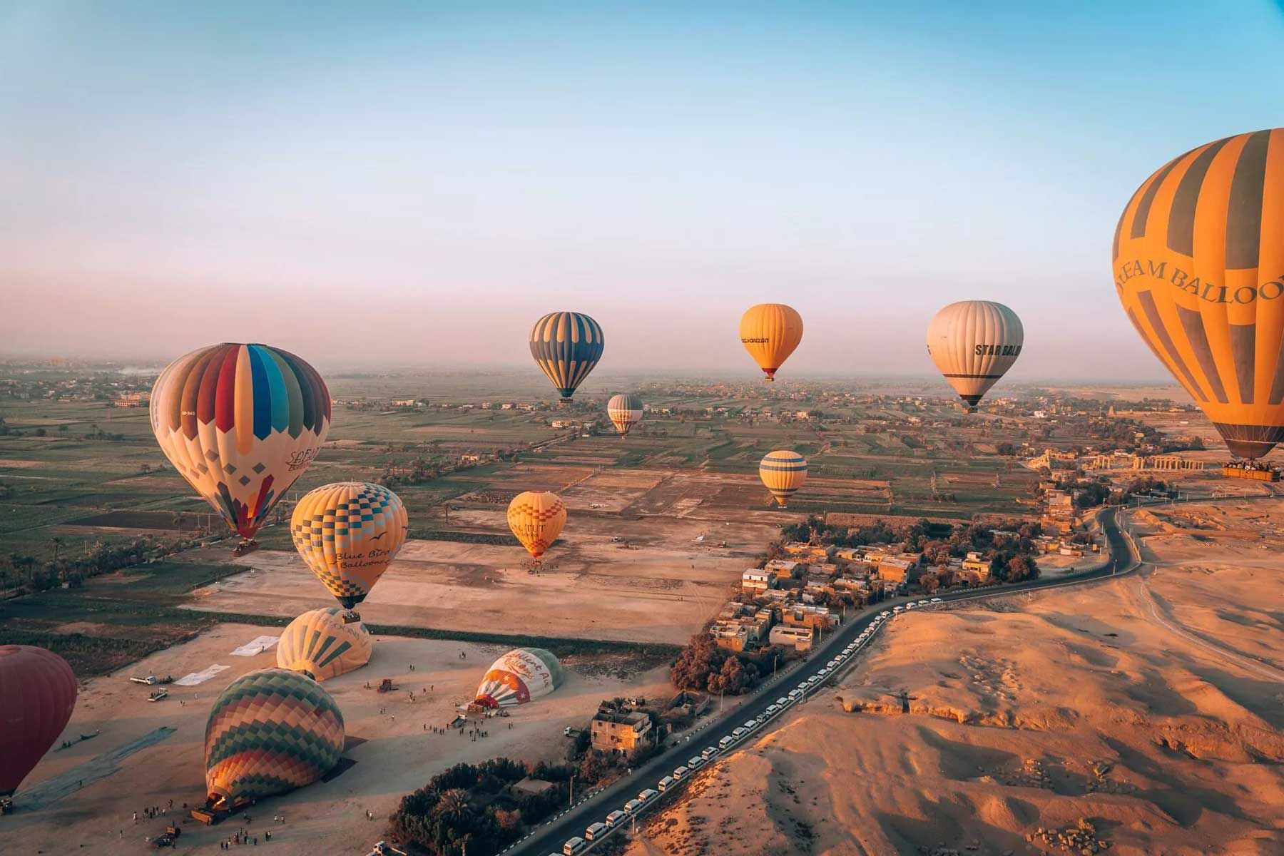 Balony na ogrzane powietrze o wschodzie słońca nad zielonymi polami i pustynią zachodniego brzegu Luksoru