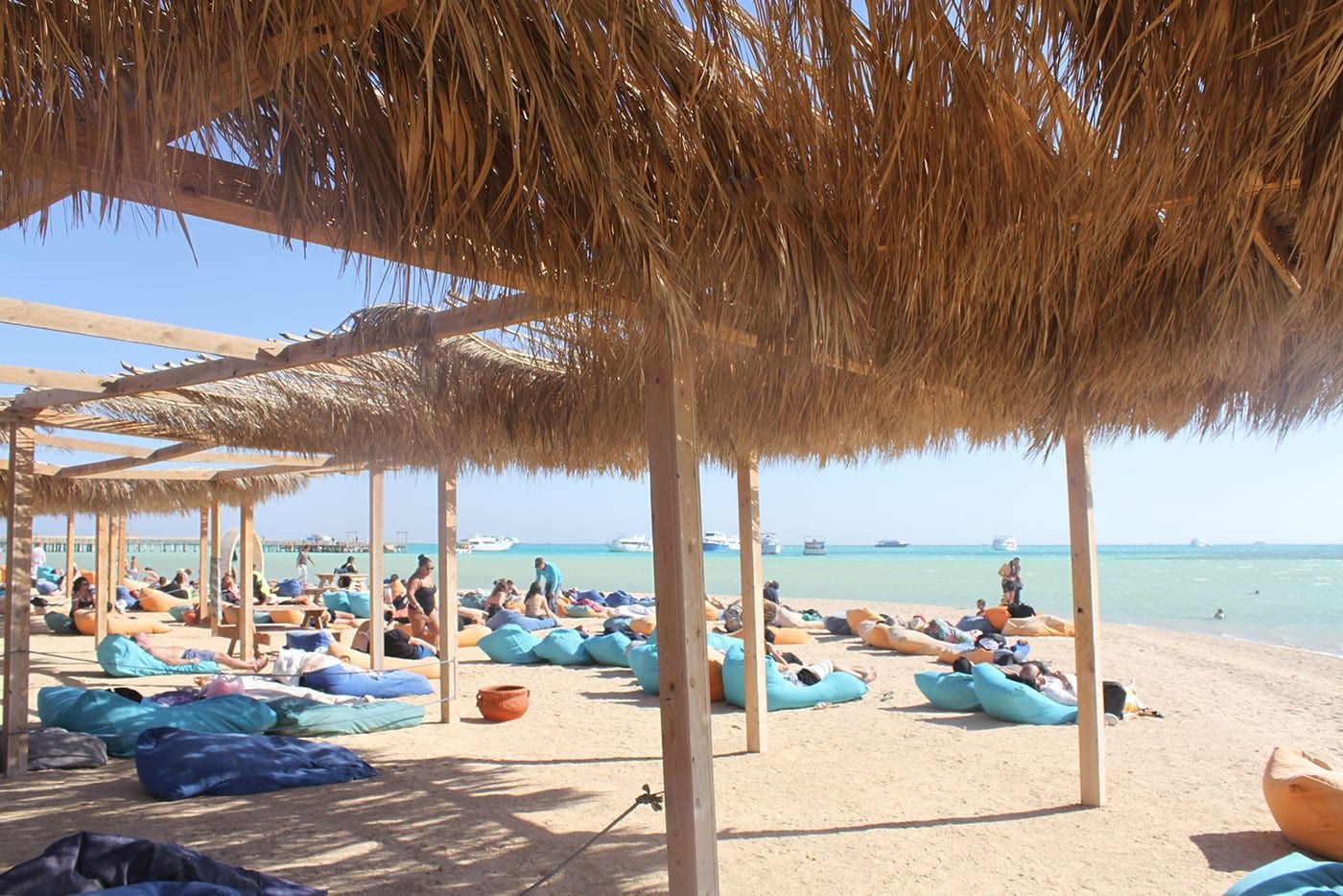 Piaszczysta plaża Orange Bay z parasolami i pufami na piasku nad turkusowym morzem