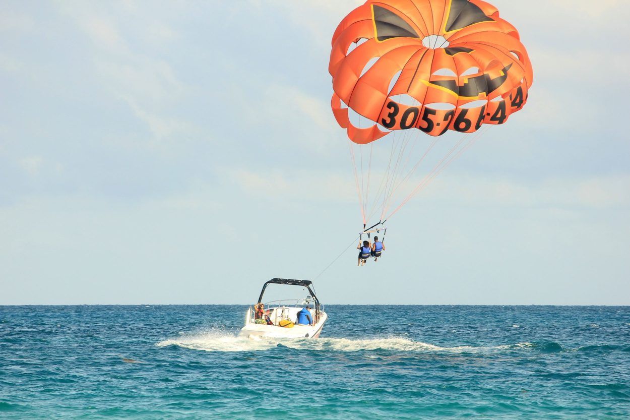 Motorówka holująca pomarańczowy spadochron parasailingowy z dwoma uczestnikami nad Morzem Czerwonym w Hurghadzie