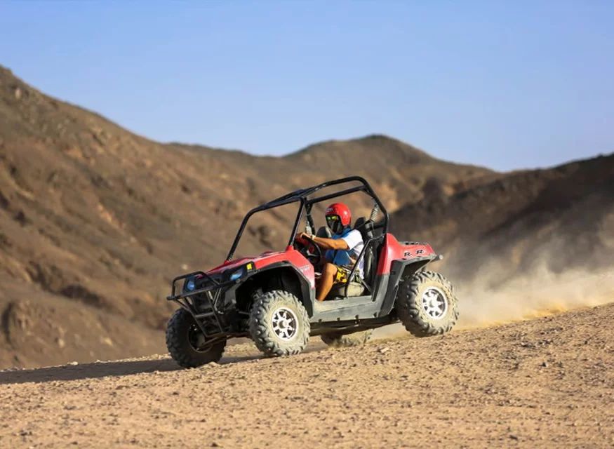 Czerwony buggy pędzący po pustyni wśród skalistych gór podczas Buggy Safari z Hurghady