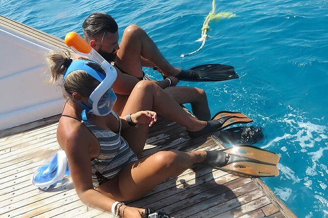 Para z pełnotwarzowymi maskami do snorkelingu i płetwami odpoczywa na rufowej platformie prywatnego speed boata