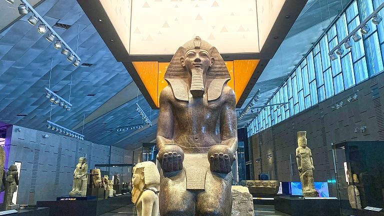 Monumentalny posąg zasiadającego faraona w galerii Wielkiego Muzeum Egipskiego (GEM) w Gizie