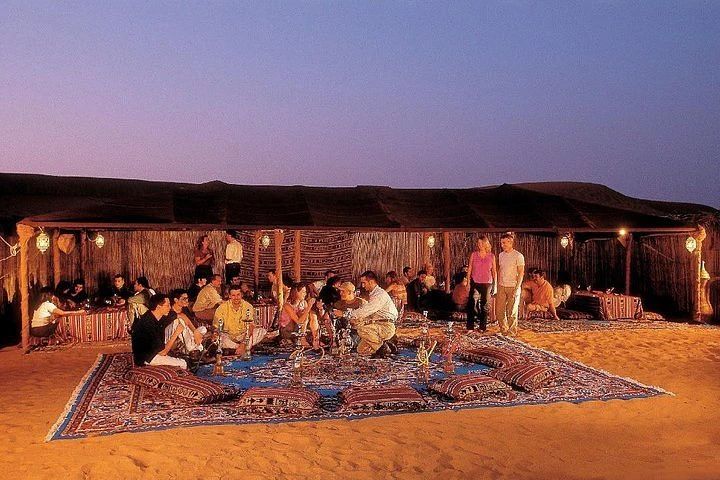 Uczestnicy odpoczywający na dywanach w beduińskim namiocie o zmierzchu podczas Jeep Safari z Marsa Alam