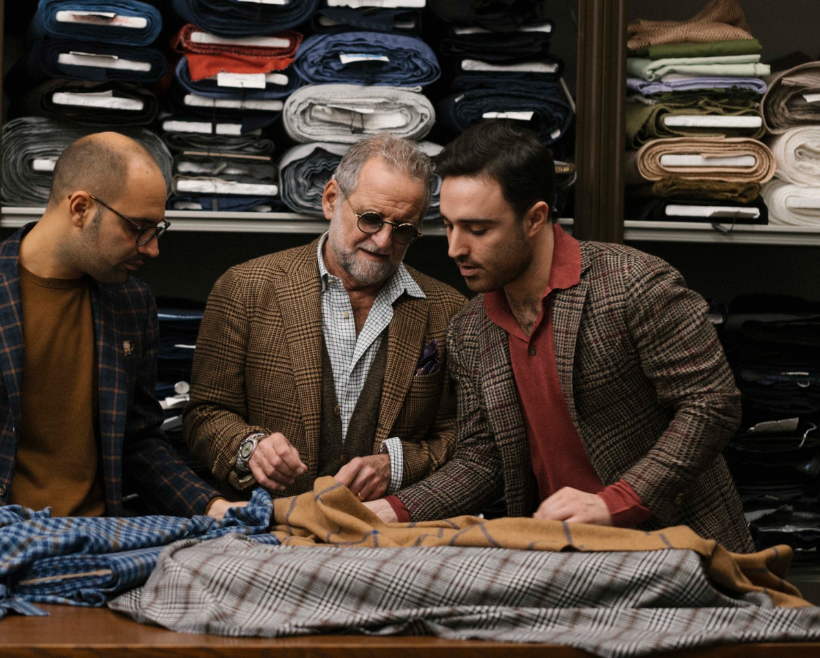 Three men in textiles workshop looking at fabric.