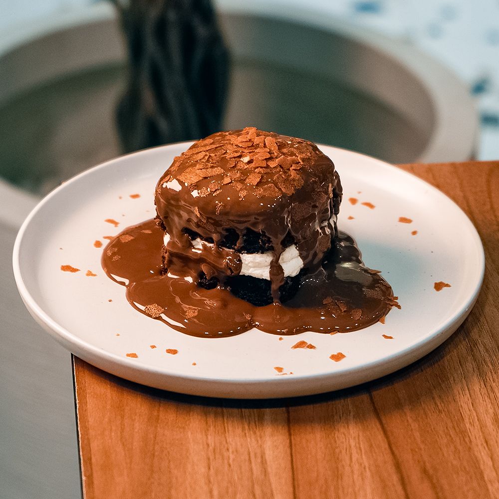 Signature Plated Asador Chocolate Brownie Layered with Cream and Drenched in Chocolate Sauce at Asador Coffee El Jadida