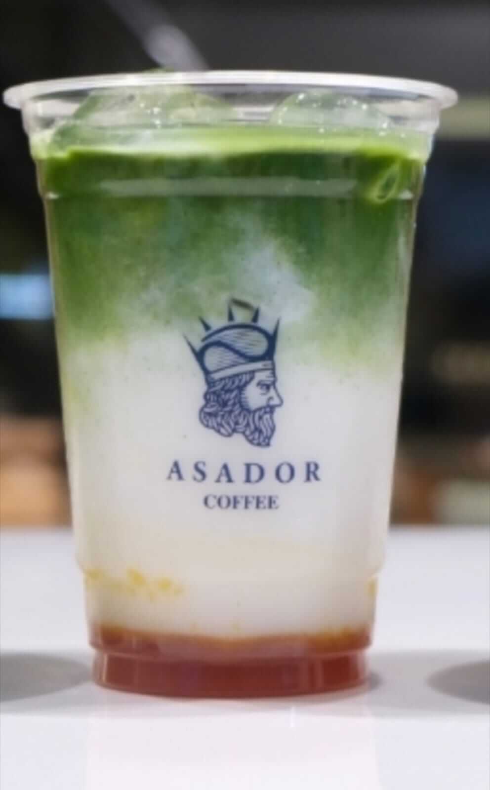 Iced Mango Matcha Latte with Layered Mango and Green Tea in Plastic Cup at Asador Coffee El Jadida