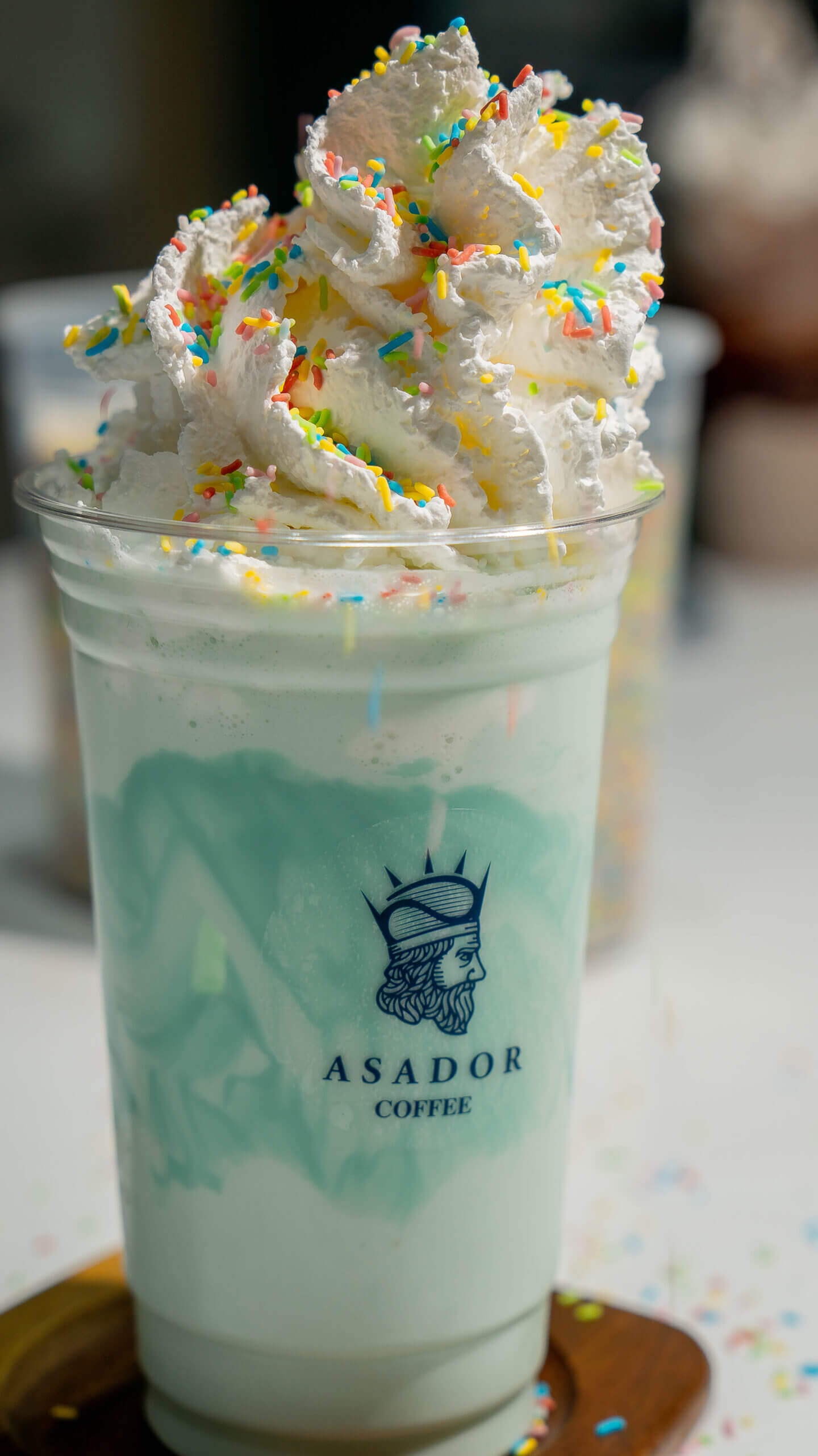 Blue Bubble Gum Milkshake with Whipped Cream and Sprinkles in Plastic Cup at Asador Coffee El Jadida