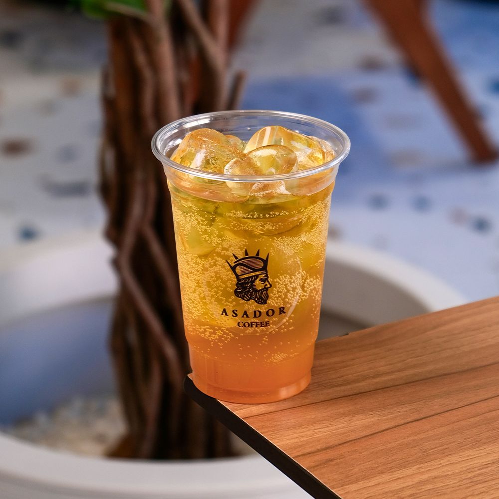 Iced Peach Energy Drink with Fresh Fruit Garnish in Plastic Cup at Asador Coffee El Jadida