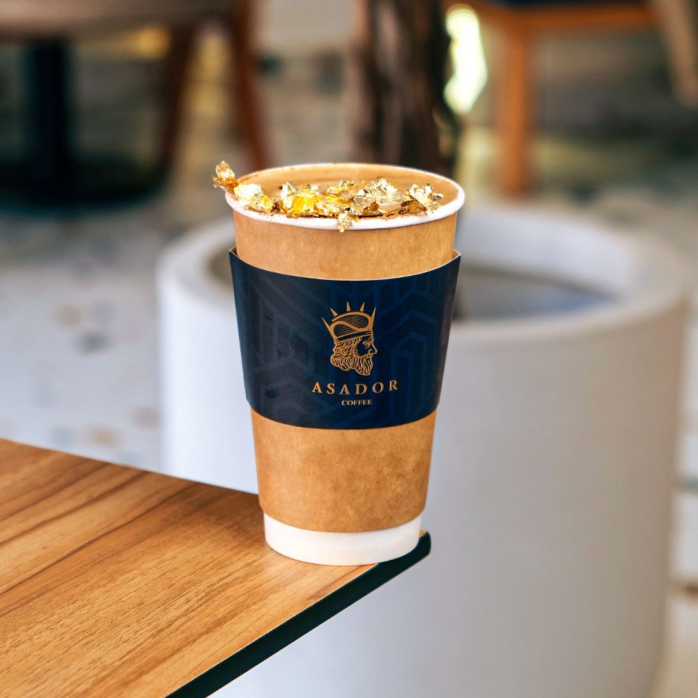 Gold Cappuccino with Edible Gold Flakes in Takeaway Cup at Asador Coffee El Jadida