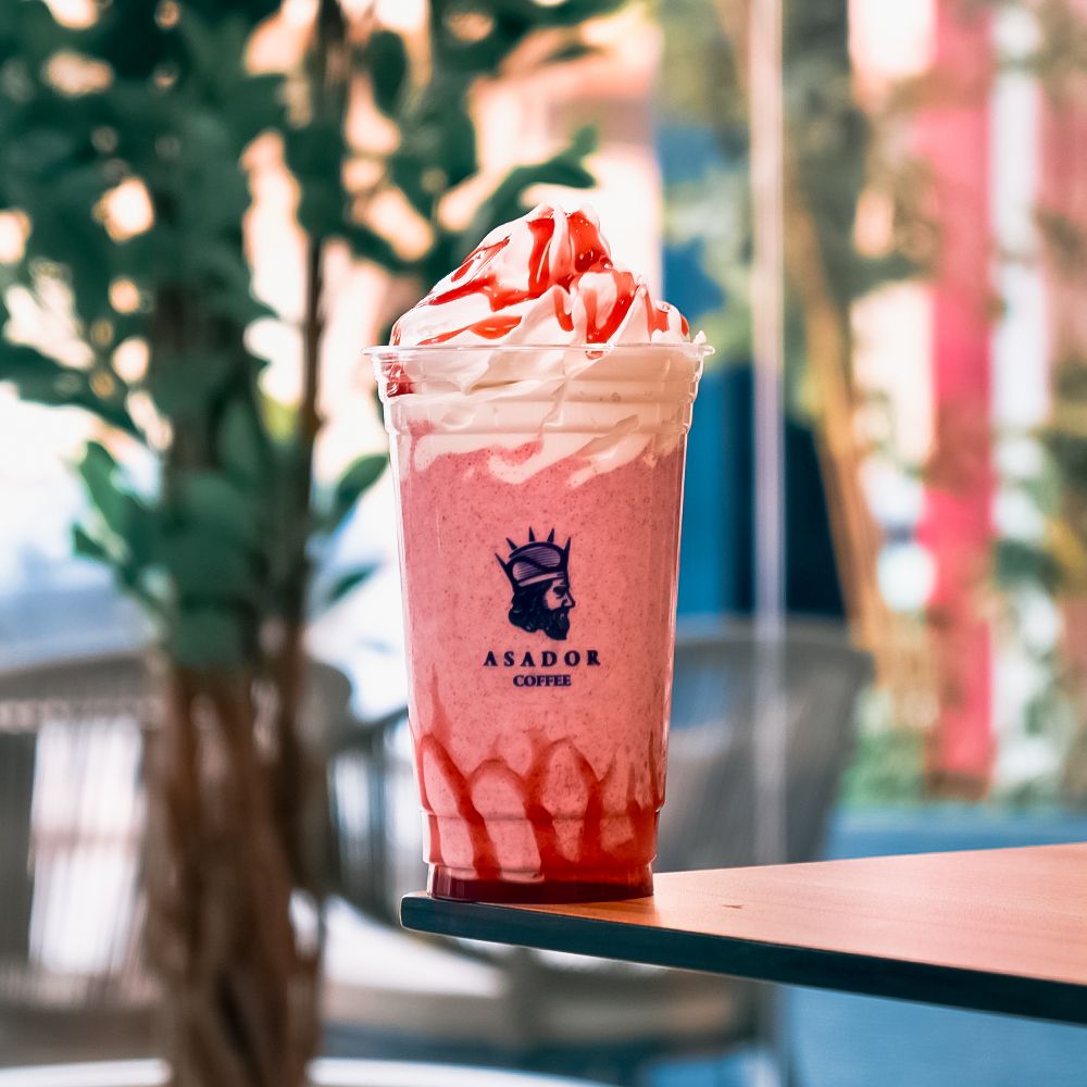 Iced Red Velvet Milkshake with Whipped Cream and Red Syrup Drizzle in Plastic Cup at Asador Coffee El Jadida
