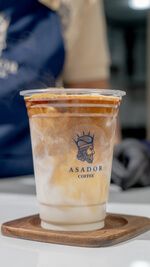 Layered Iced Latte in Plastic Takeaway Cup with Barista Hand at Asador Coffee El Jadida