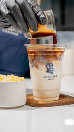 Barista Pouring Espresso into Iced White Mocha Coffee in Plastic Cup at Asador Coffee El Jadida