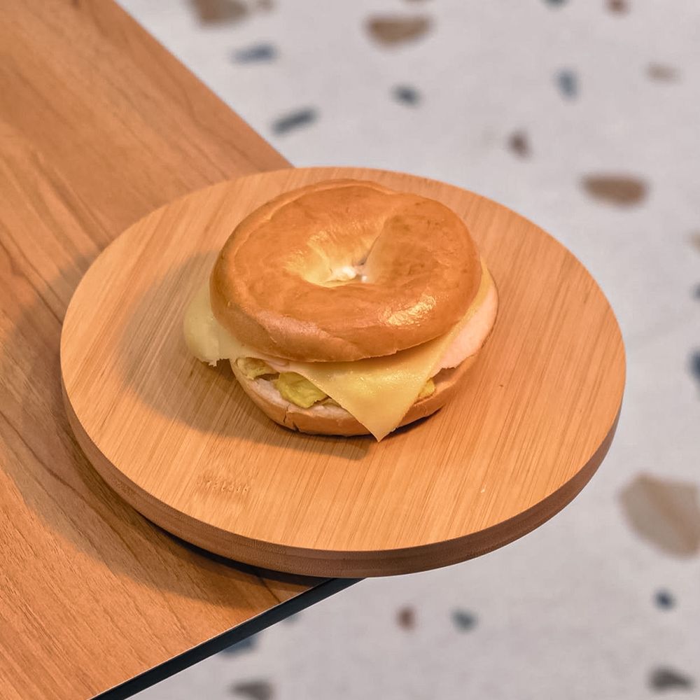 Toasted Bagel Sandwich with Egg Cheese and Smoked Turkey on Wooden Board at Asador Coffee El Jadida