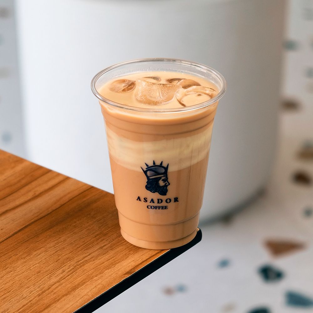 Barista Pouring Espresso into Iced White Mocha Coffee in Plastic Cup at Asador Coffee El Jadida