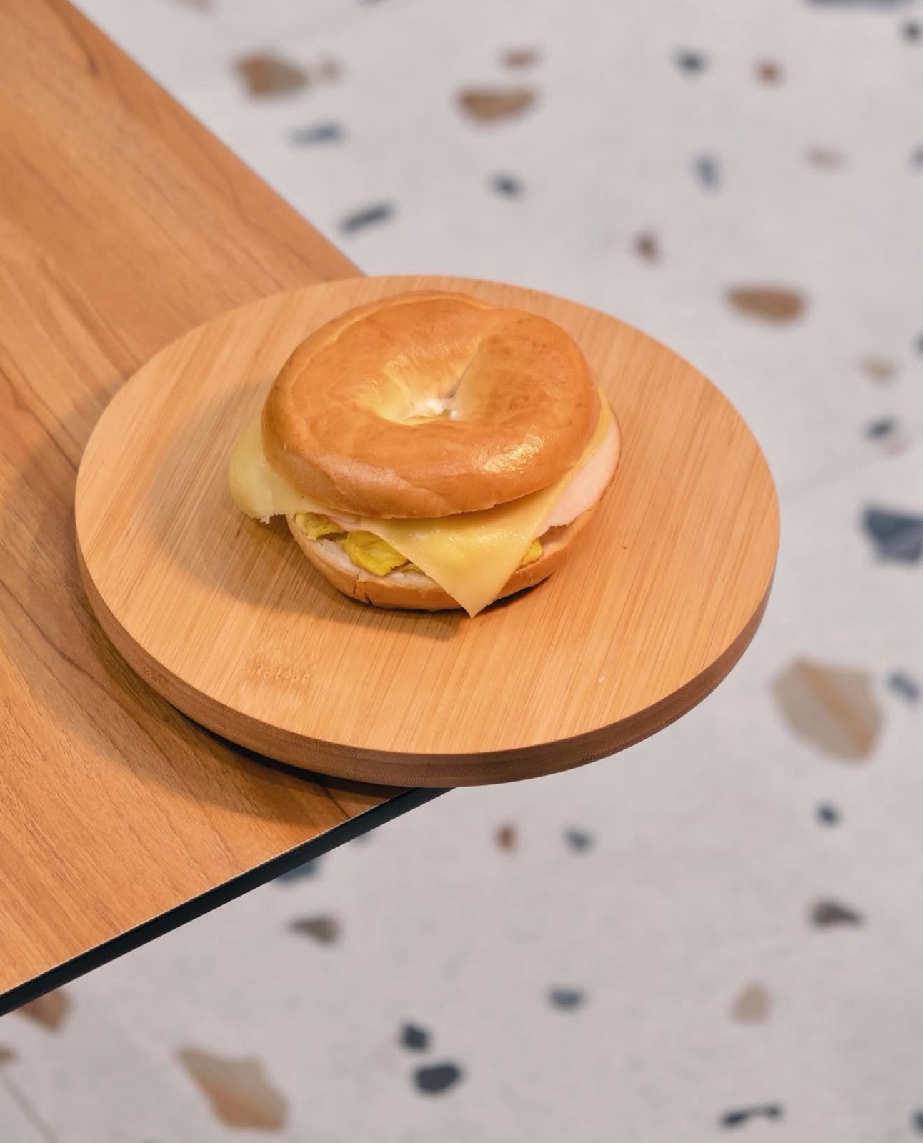 Toasted Bagel Sandwich with Egg Cheese and Smoked Turkey on Wooden Board at Asador Coffee El Jadida