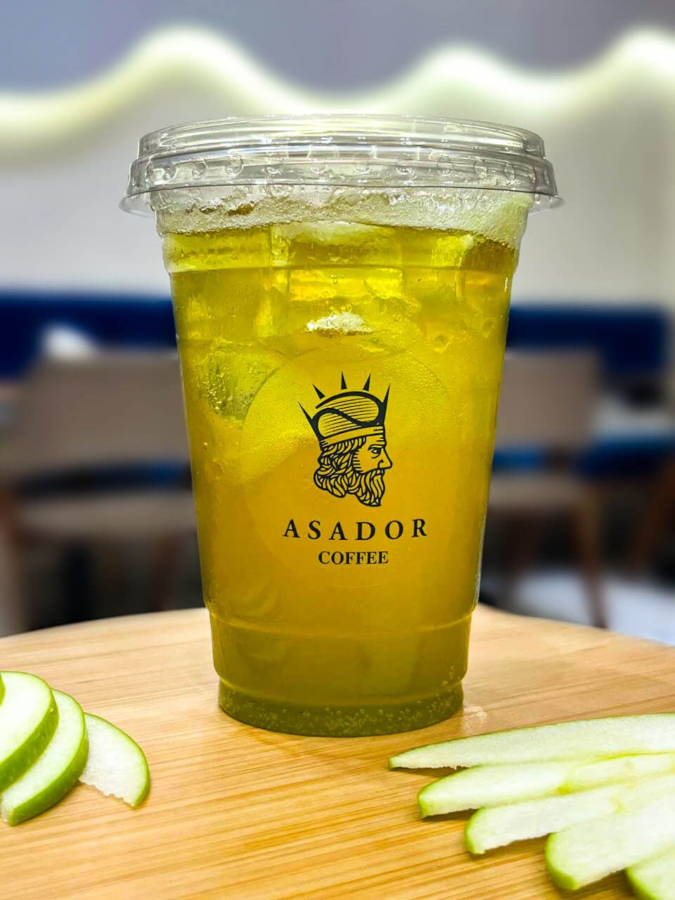 Iced Green Apple Energy Drink with Apple Slices in Plastic Cup at Asador Coffee El Jadida