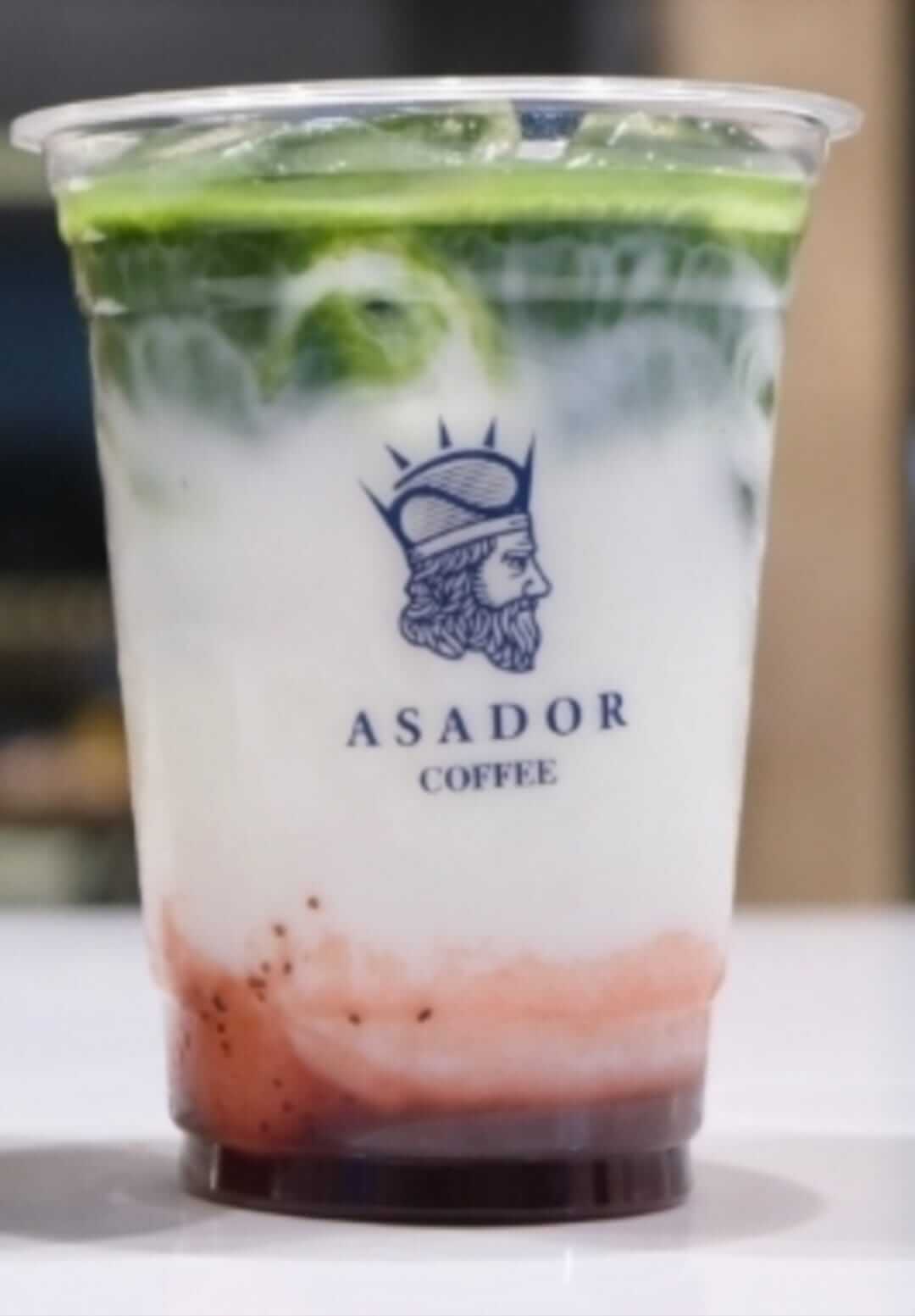 Iced Strawberry Matcha Latte with Pink and Green Layers in Plastic Cup at Asador Coffee El Jadida