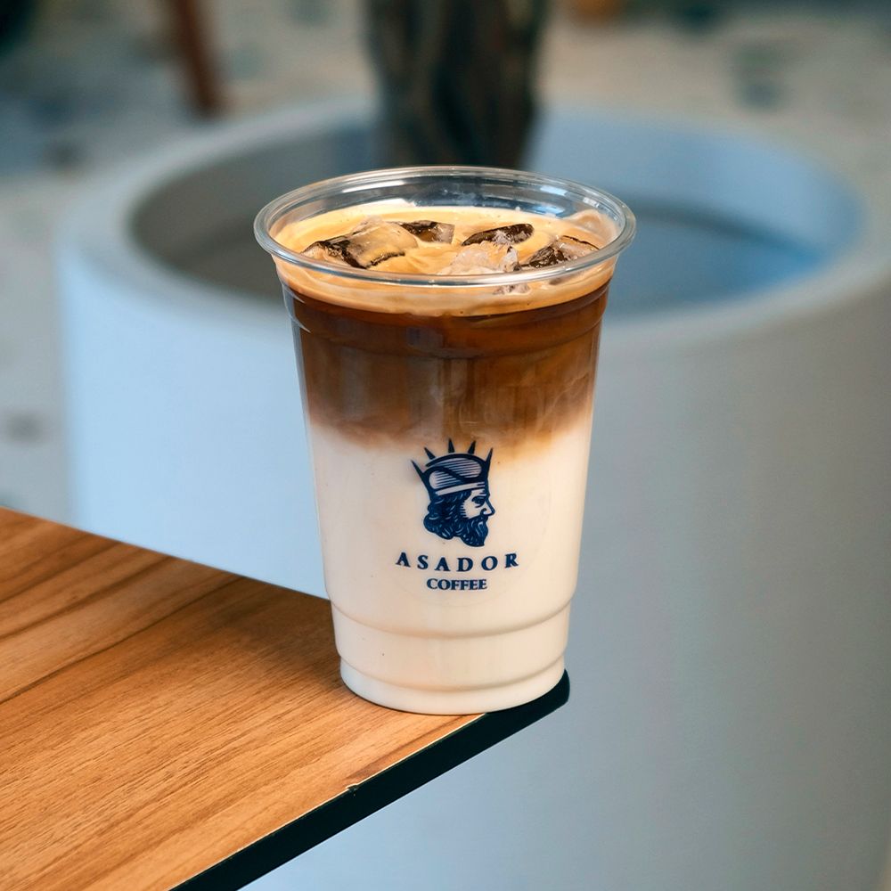 Layered Iced Latte in Plastic Takeaway Cup with Barista Hand at Asador Coffee El Jadida
