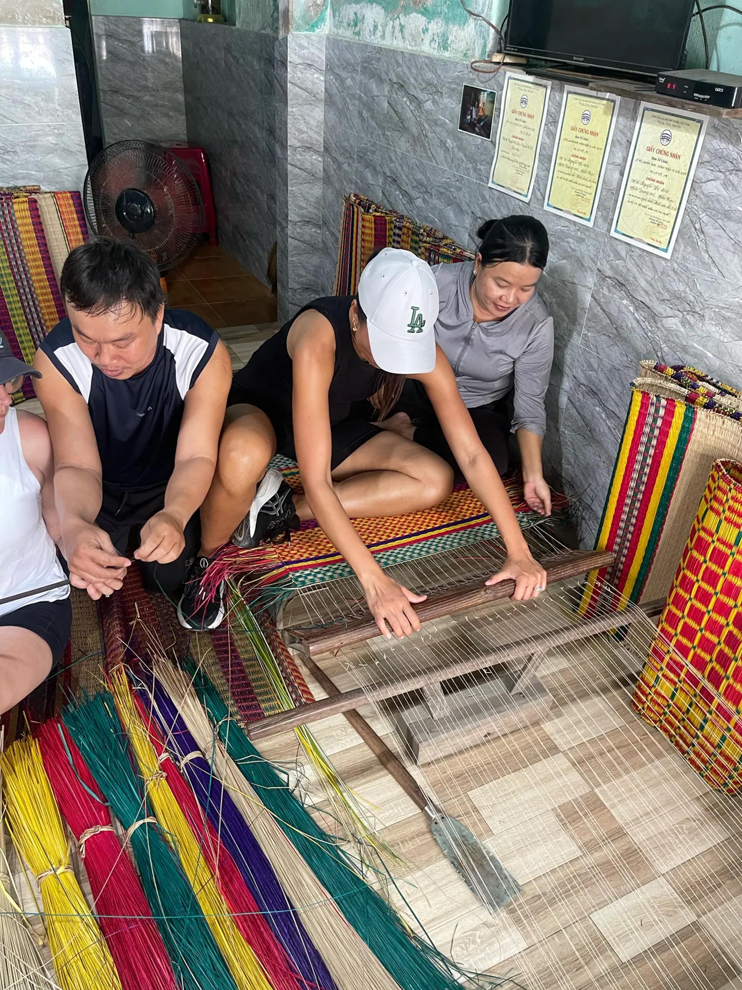 Guests trying the traditional mat loom with a local weaver