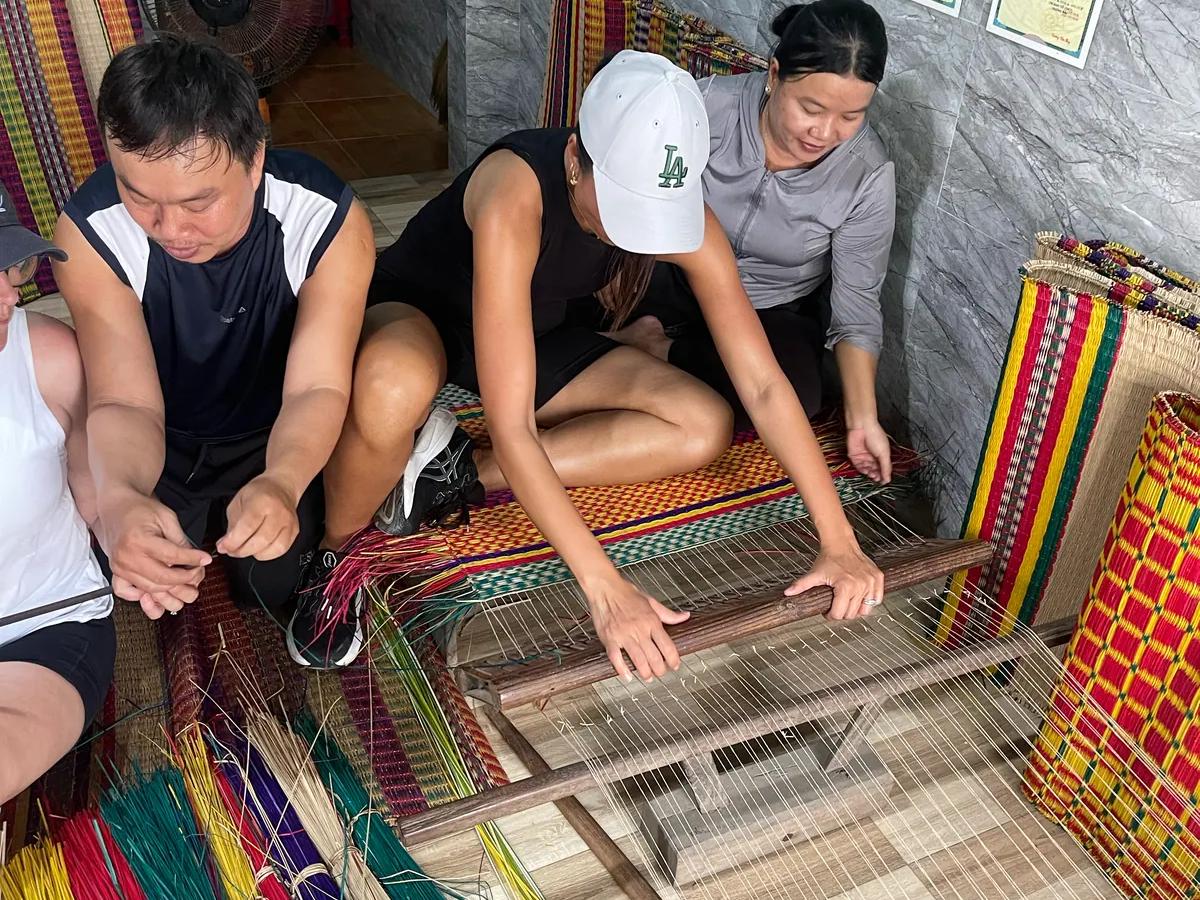 Guests trying the traditional mat loom with a local weaver