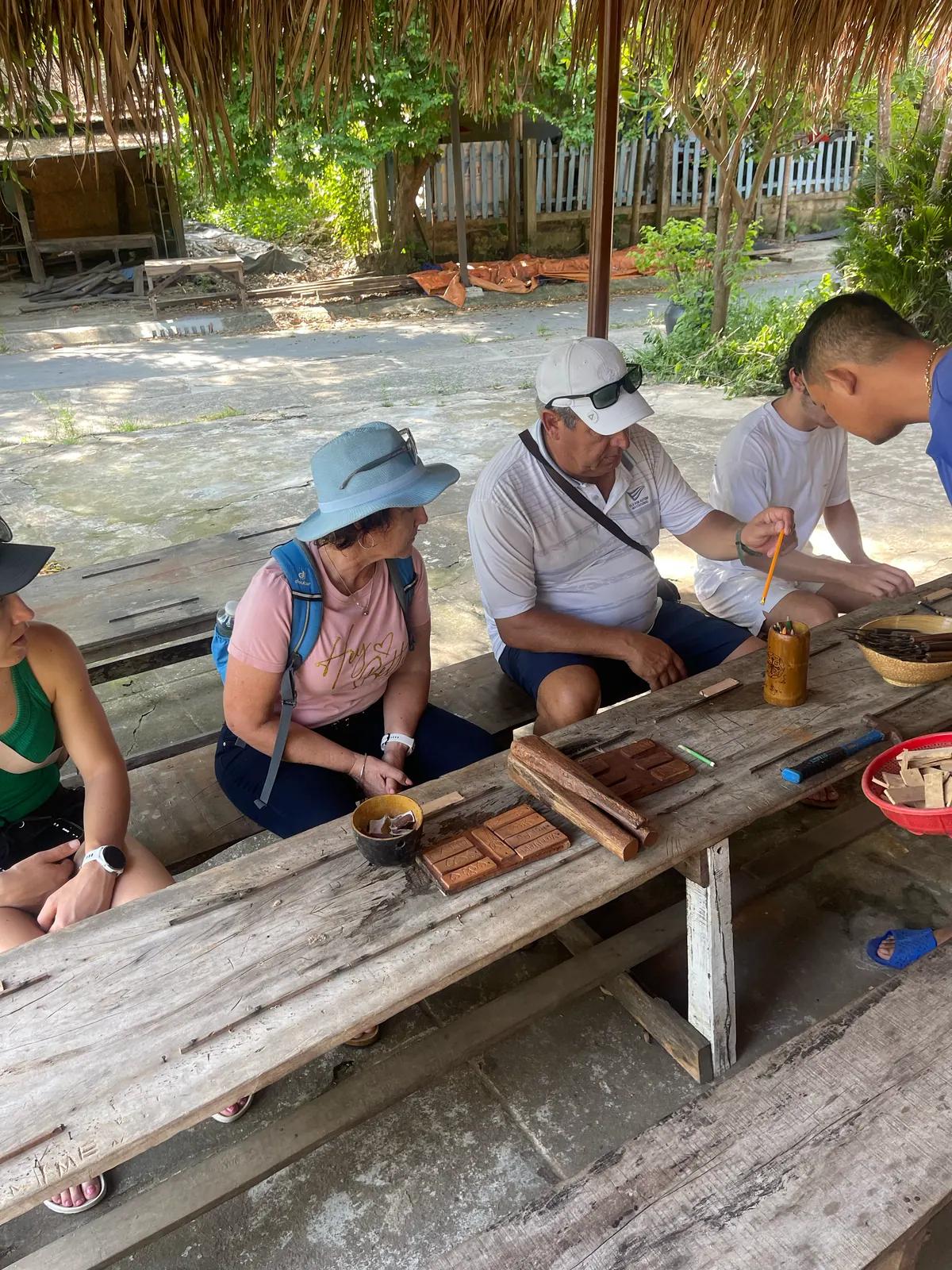 Guests carving wood with an artisan in the Kim Bong carpentry village
