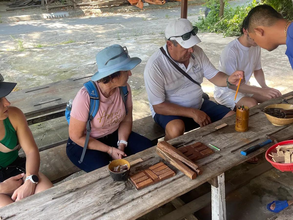 Guests carving wood with an artisan in the Kim Bong carpentry village