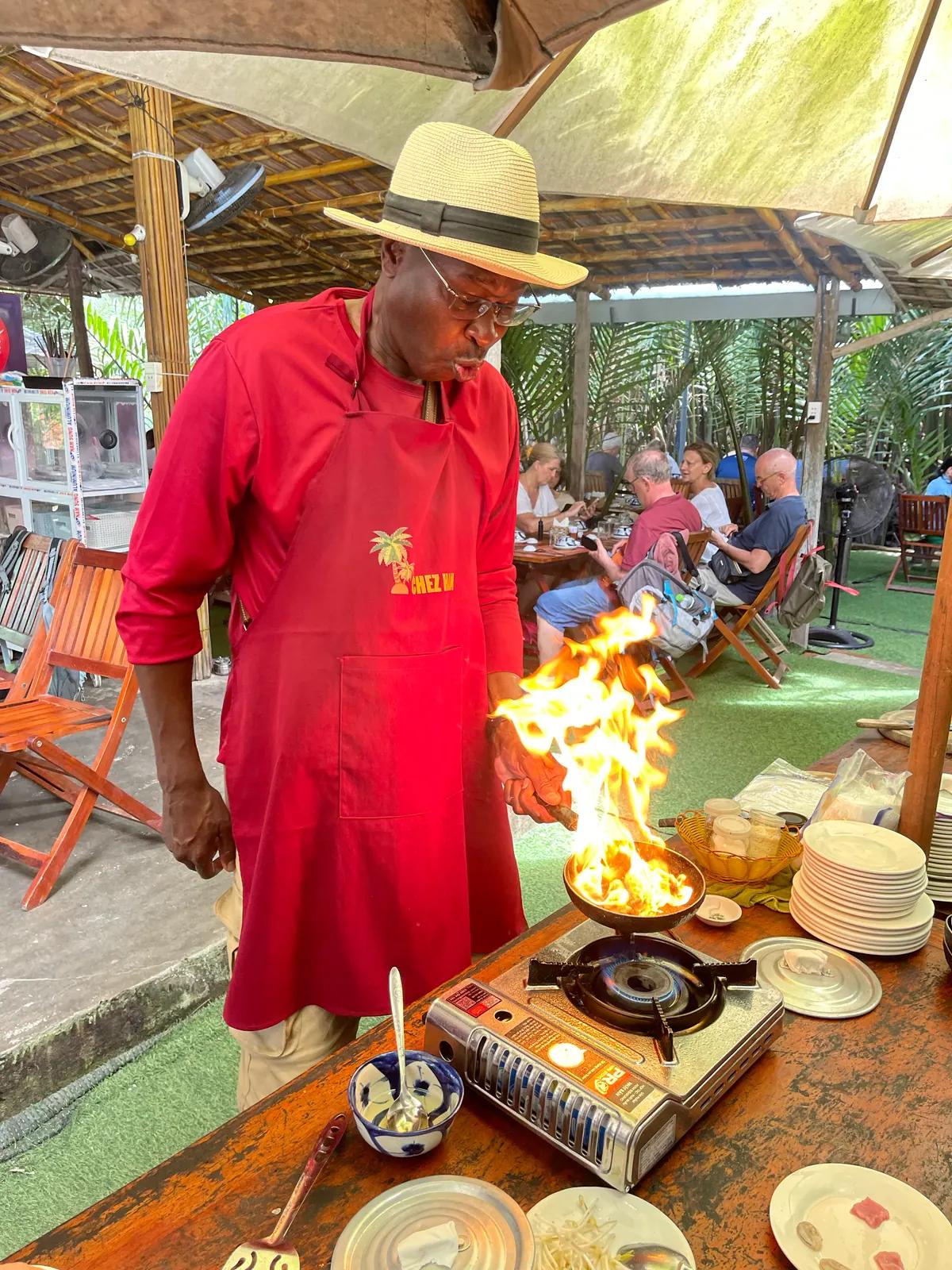 A guest cooking over an open flame at the village cooking class