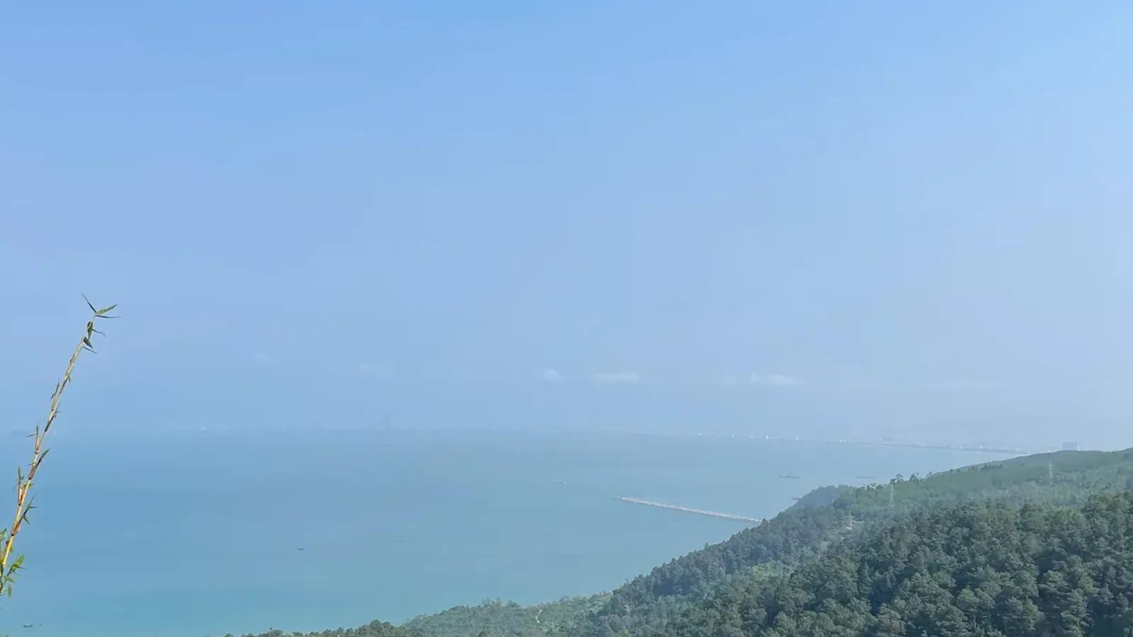 Forested slopes and a hazy blue bay viewed from Hai Van Pass