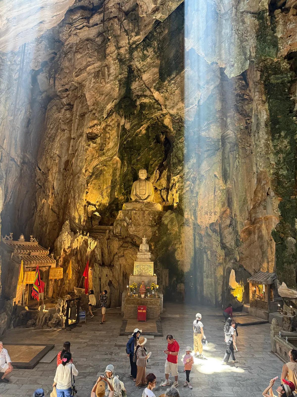 Sunlight entering Huyen Khong Cave above its Buddhist shrine and visitors