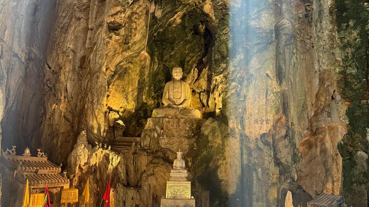 Sunlight entering Huyen Khong Cave above its Buddhist shrine and visitors