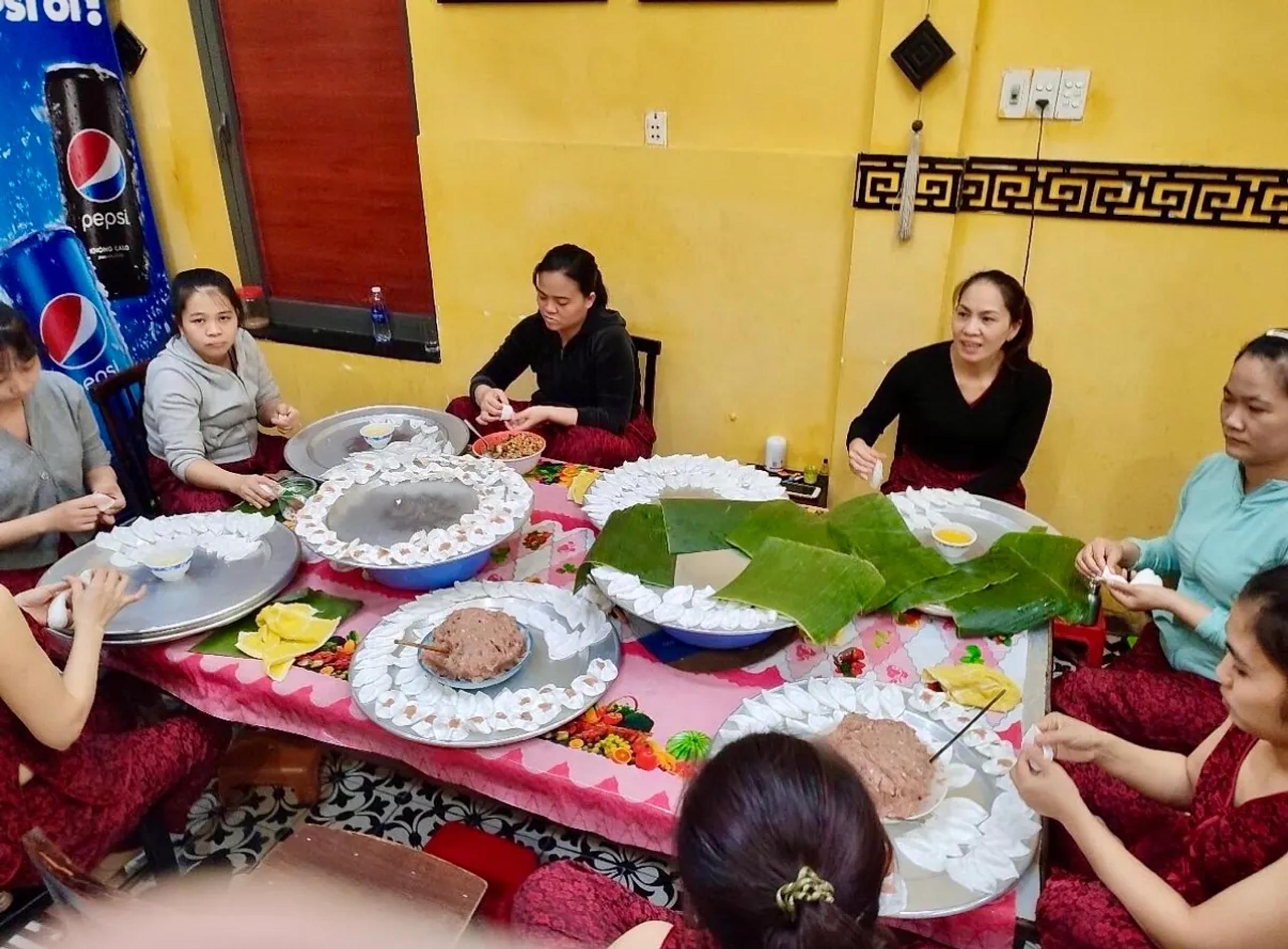 Local cooks folding white rose dumplings around a shared table in a Hoi An family kitchen